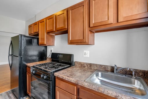 a kitchen with wood cabinets and black appliances and a sink