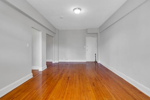 an empty living room with wood floors and white walls