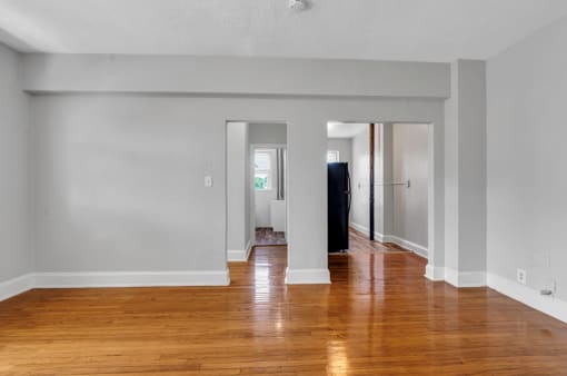 an empty living room with wood floors and white walls