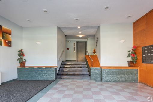 A hallway with a checkered floor and a staircase.