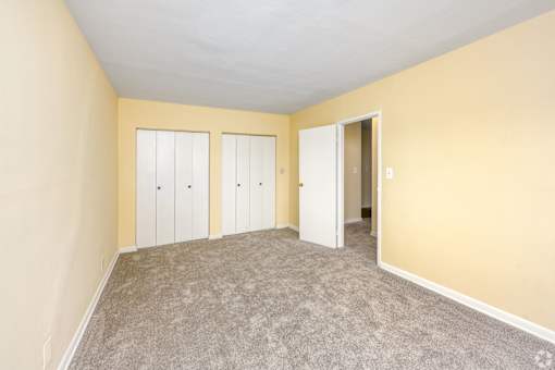 A room with a carpeted floor and two white doors.
