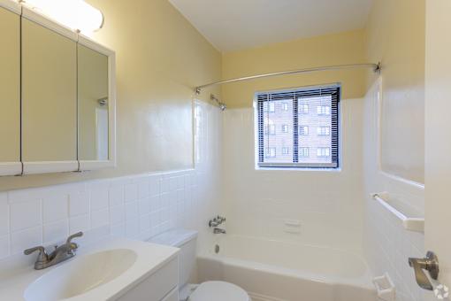 A white sink and tub in a bathroom with a window.