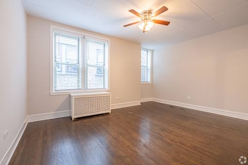 A room with a ceiling fan and a window with blinds.