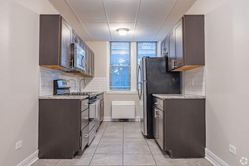 A kitchen with brown cabinets and a black refrigerator.