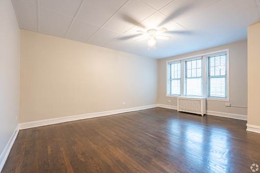 A room with a ceiling fan and a window with blinds.