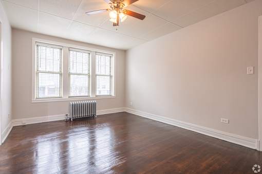 A room with a ceiling fan and a radiator beneath a window.