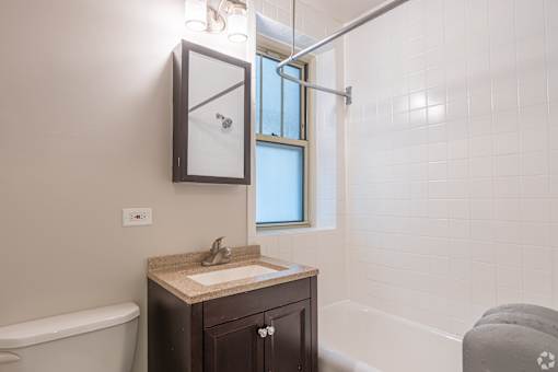 A bathroom with a sink, mirror, and bathtub.