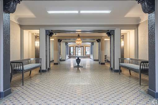 A hallway with a tiled floor and benches on either side.
