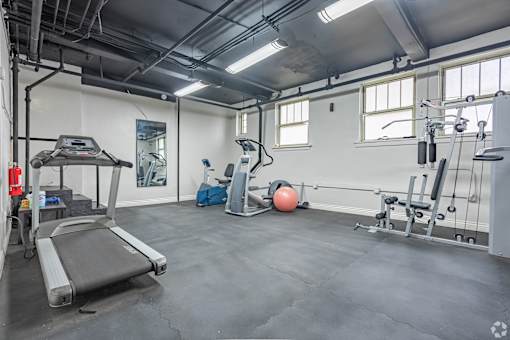 A gym with a treadmill, weights, and exercise balls.