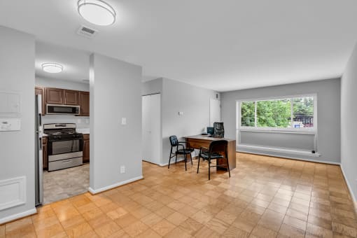 an empty living room with a kitchen and a table with chairs