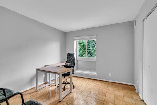 an empty room with a desk and a chair and a window
