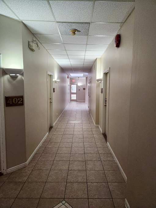A long hallway with doors on both sides and a fire extinguisher on the wall.