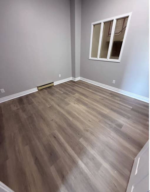 A room with wooden flooring and a window.