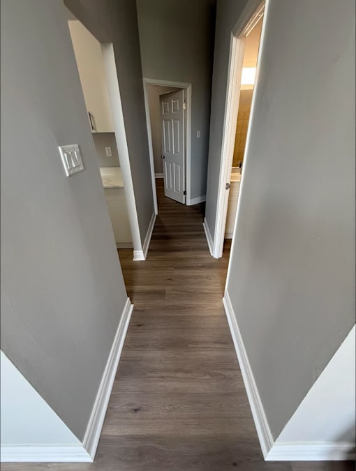 A long hallway with white walls and wood floors.