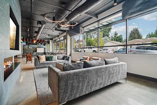 A grey couch is in the middle of a room with a lot of windows.