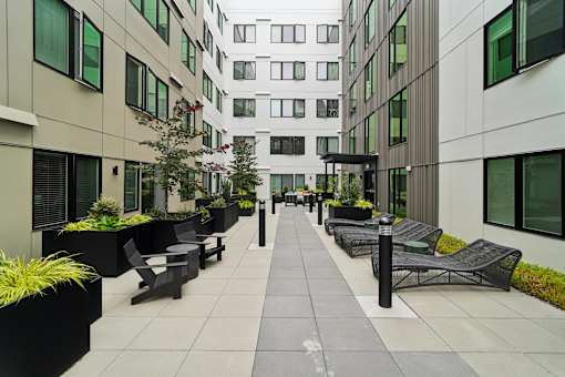 A long walkway between two buildings with benches on either side.