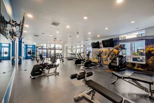 A gym with a variety of equipment including treadmills, weights, and exercise machines.