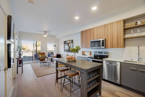A modern kitchen with a wooden bar and stools.