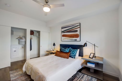 A bedroom with a bed, a nightstand, and a ceiling fan.