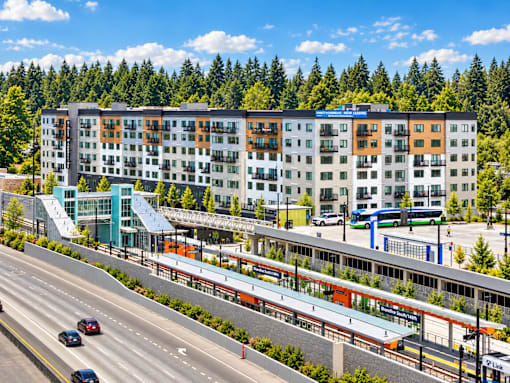 A modern multi-story building with a parking garage in front of it.