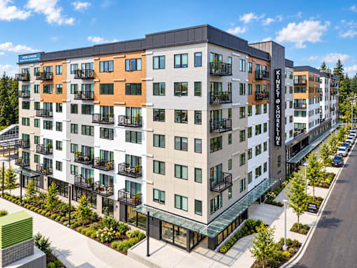 A modern apartment building with balconies and a green area in front.