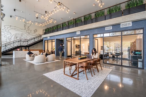 A modern interior with a wooden table and chairs, a staircase, and a balcony with plants.