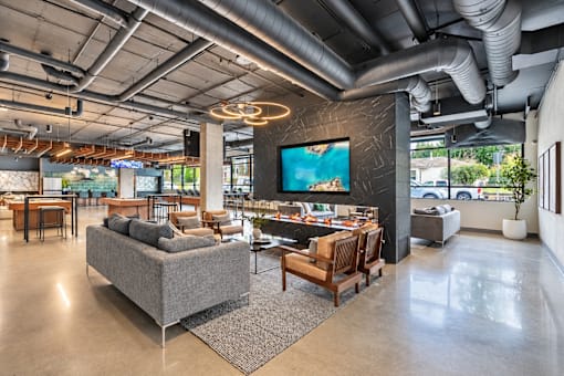 A modern living room with a grey sofa and a large TV mounted on the wall.