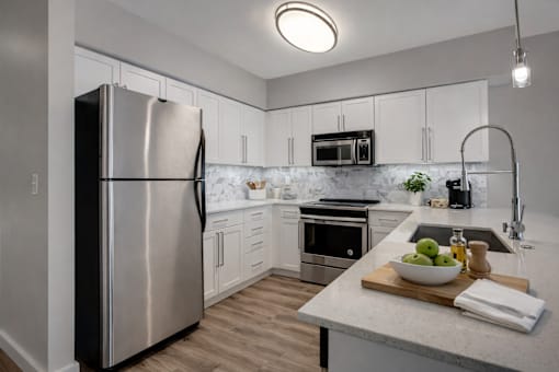 A modern kitchen with a stainless steel refrigerator and a marble countertop.