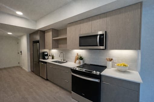 A modern kitchen with a black stove top oven and a microwave above the sink.