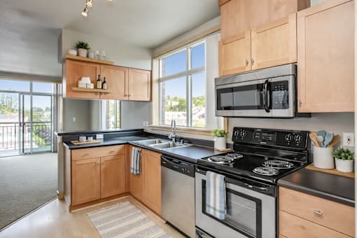 A kitchen with a black stove top oven and a black microwave above it.