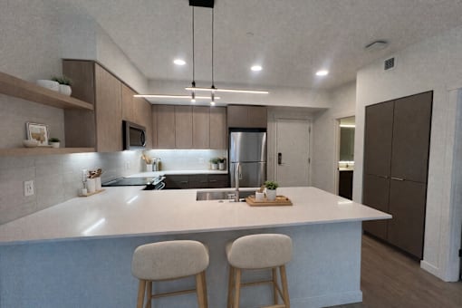 A modern kitchen with a large island and two stools.