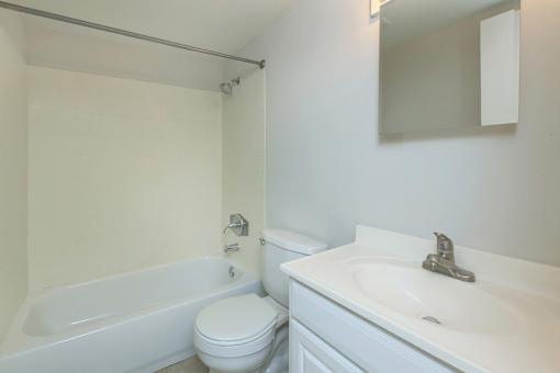 A white bathroom with a toilet, sink, and bathtub.