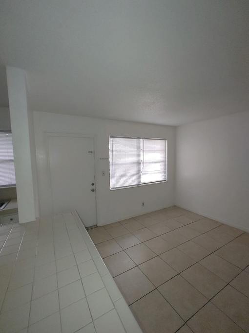 A room with a tiled floor and a window with blinds.