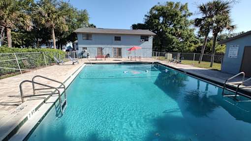 A swimming pool with a diving board and a building in the background.