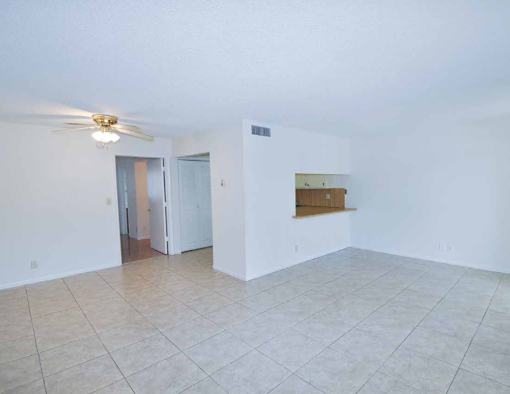 A room with a ceiling fan and a door leading to another room.