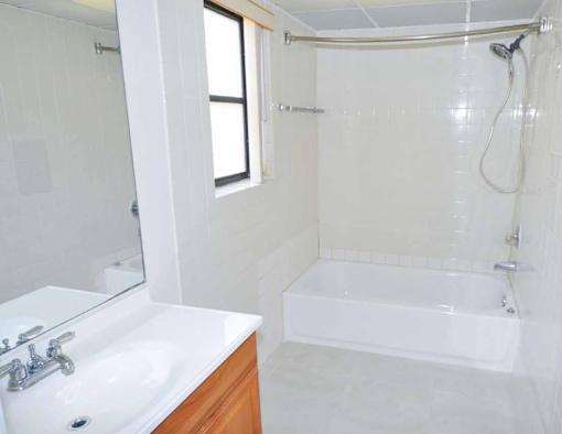 A white bathroom with a tub, sink, and mirror.