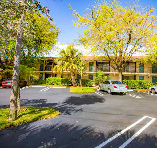 A parking lot with a building in the background and a tree with yellow leaves.