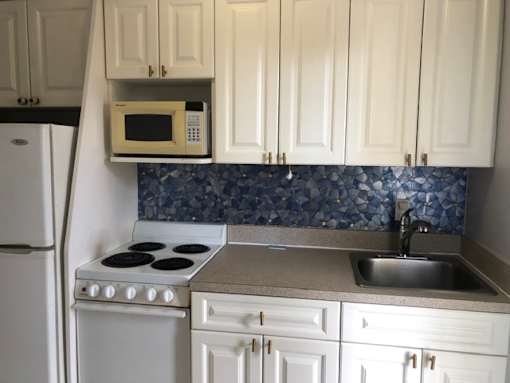 A kitchen with white cabinets and a blue tile backsplash.