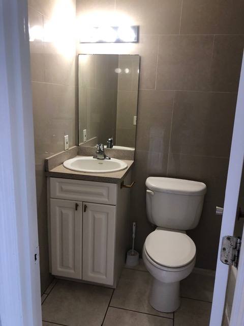A bathroom with a toilet, sink, and mirror.
