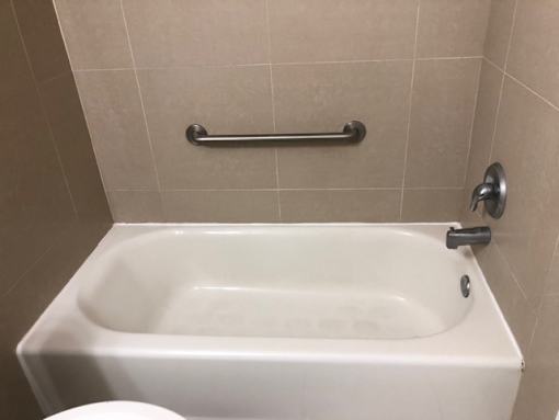 A white bathtub with a silver faucet and grab bar in a bathroom.