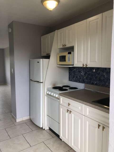 A small oven is built into a kitchen cabinet.