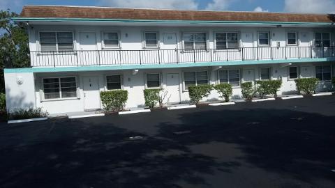 A white building with a balcony and plants in front.