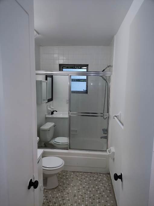 A white bathroom with a toilet, sink, and shower.