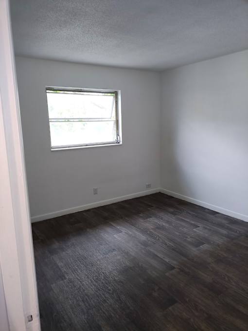 A room with a window and wooden flooring.
