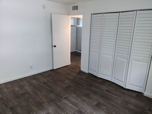 A room with a white door and a white wardrobe with a mirror.