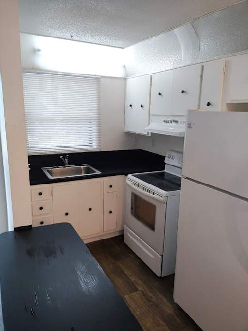 A kitchen with white appliances and black countertops.