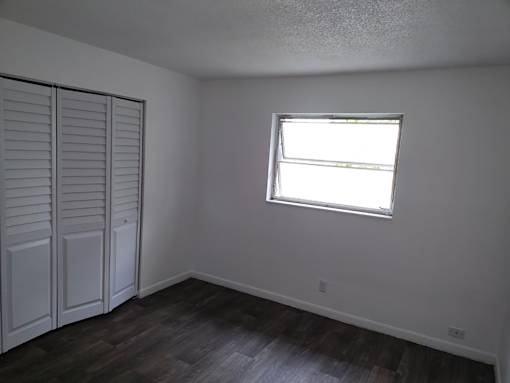 A room with a window and a wooden floor.