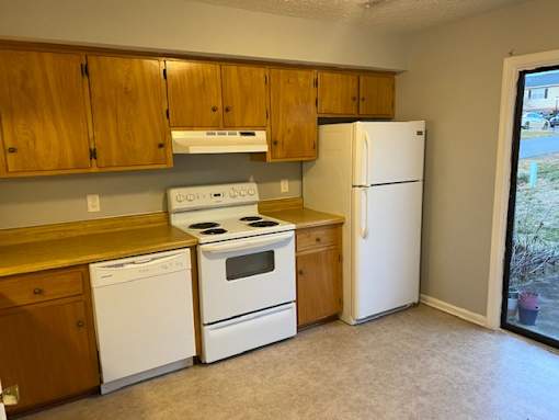 A kitchen with white appliances and wooden cabinets.