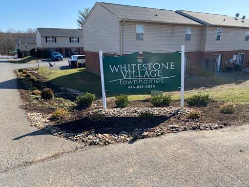 A sign for Whitestone Village is in front of some houses.
