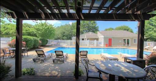 A pool area with a table and chairs under a roof.